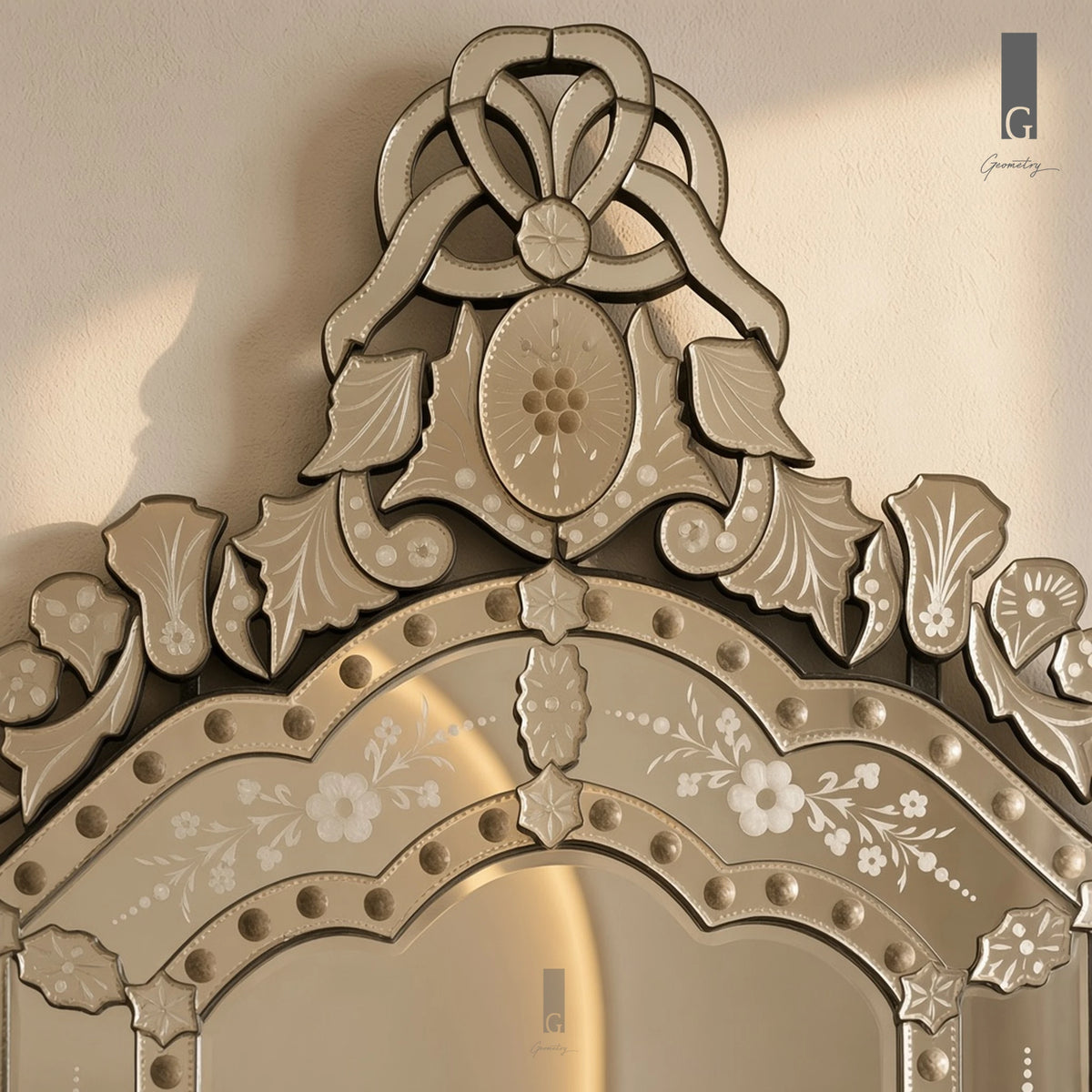 Geometry Designs Venetian Mirror crest in etched silver glass, shown in a close-up of the ribbon loops, oval medallion and glass studs.